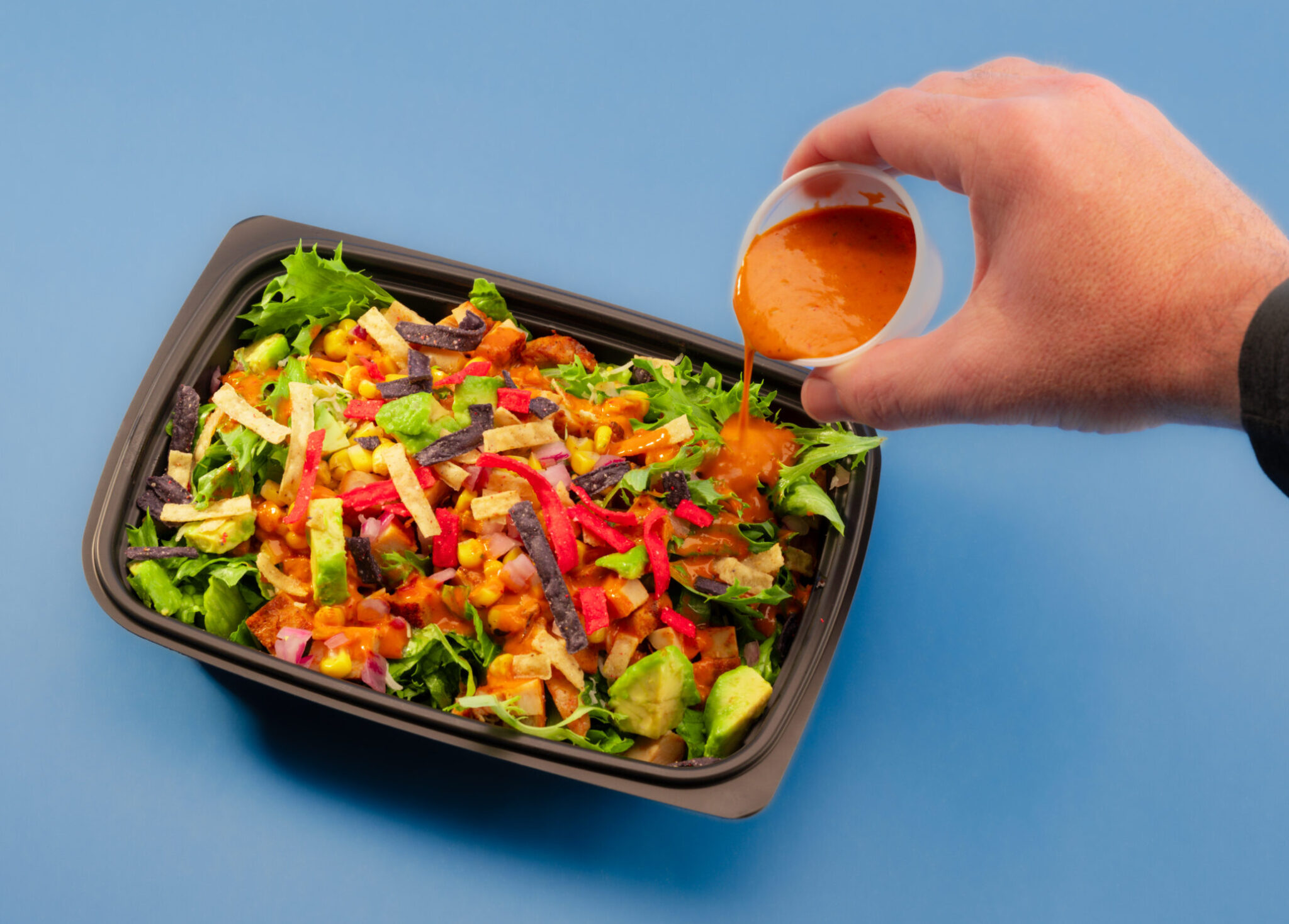 Freebirds Agave Adobo Salad with dressing poured over chicken, avocado, corn salsa, and tortilla strips