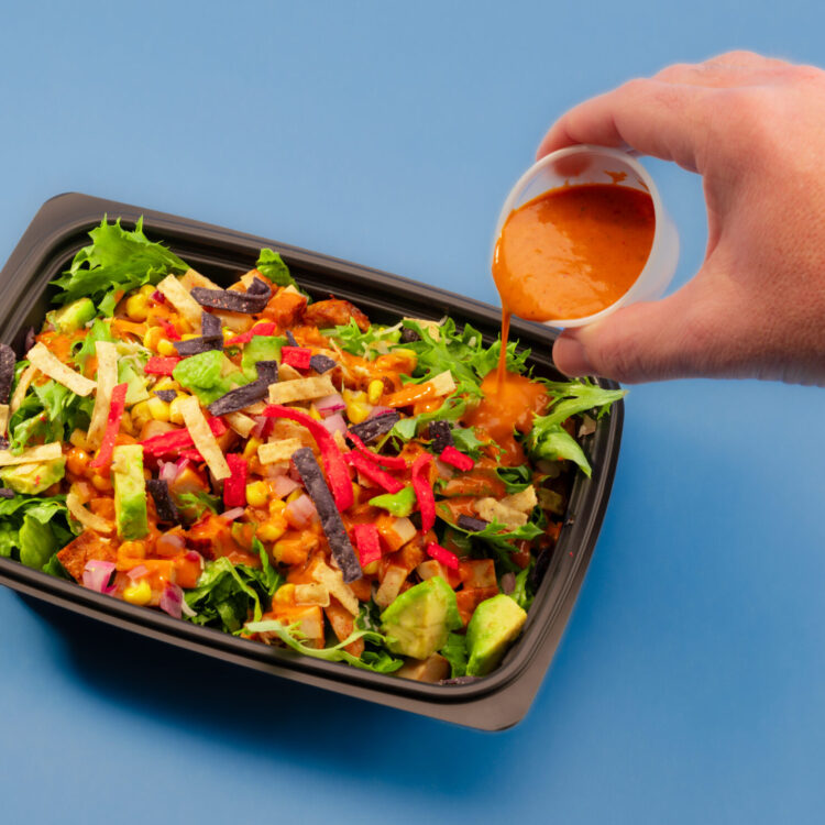 Freebirds Agave Adobo Salad with dressing poured over chicken, avocado, corn salsa, and tortilla strips