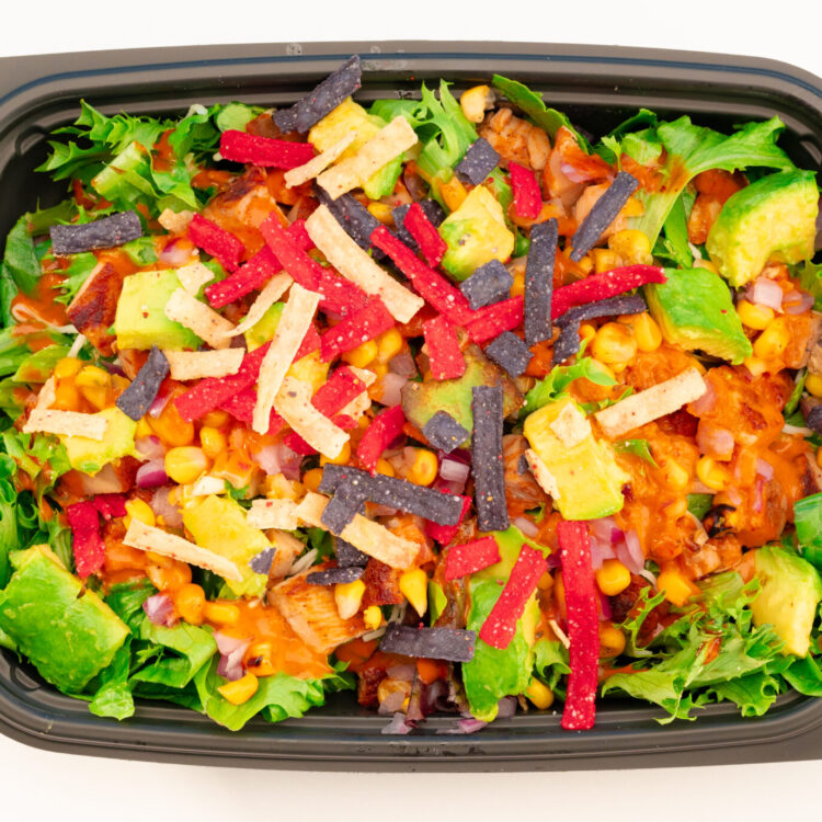 Overhead food photography of Freebirds Agave Adobo Salad with chicken, avocado, corn salsa, and tortilla strips