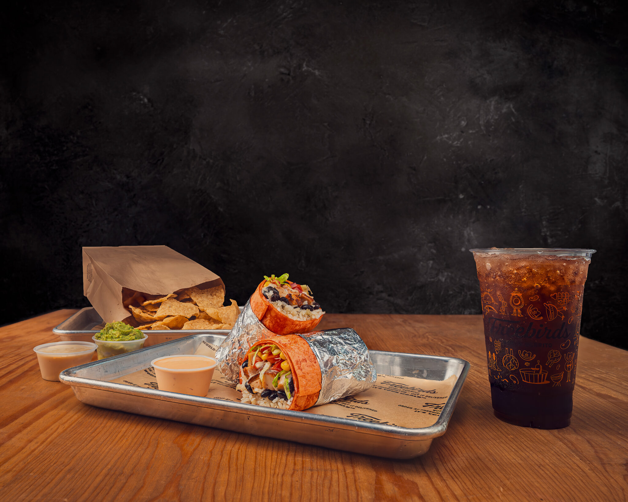 Freebirds It’s Your World campaign image with burrito, chips, sauces, and drink