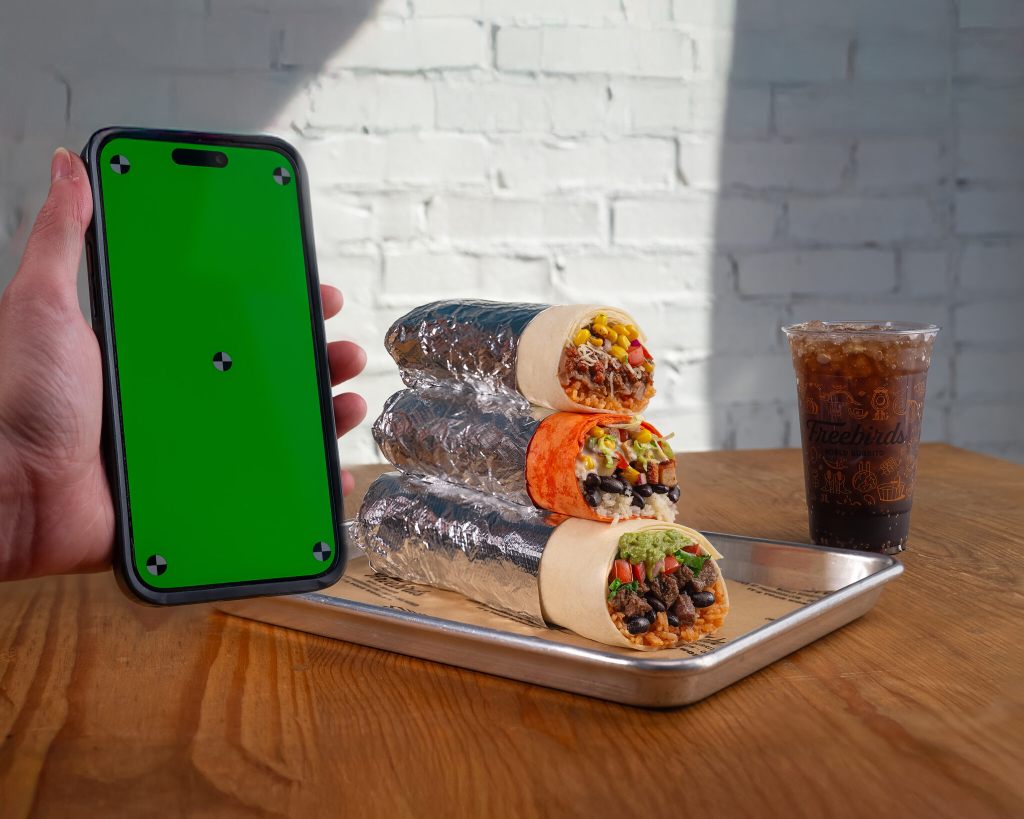 Freebirds stacked burritos with drink and phone screen for app campaign placement