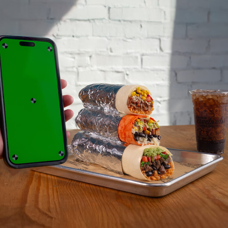 Freebirds stacked burritos with drink and phone screen for app campaign placement
