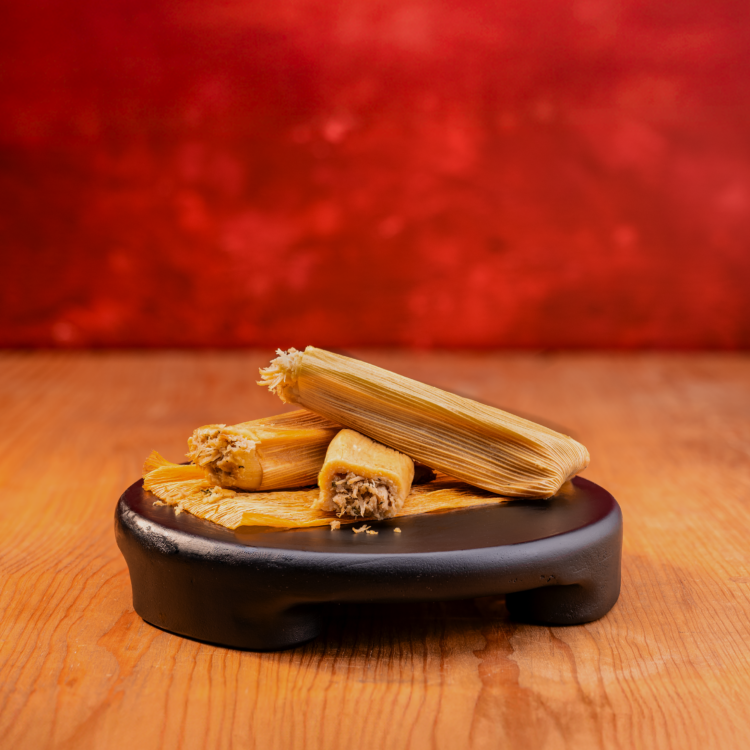 Taco Bueno chicken tamales stacked on black serving board