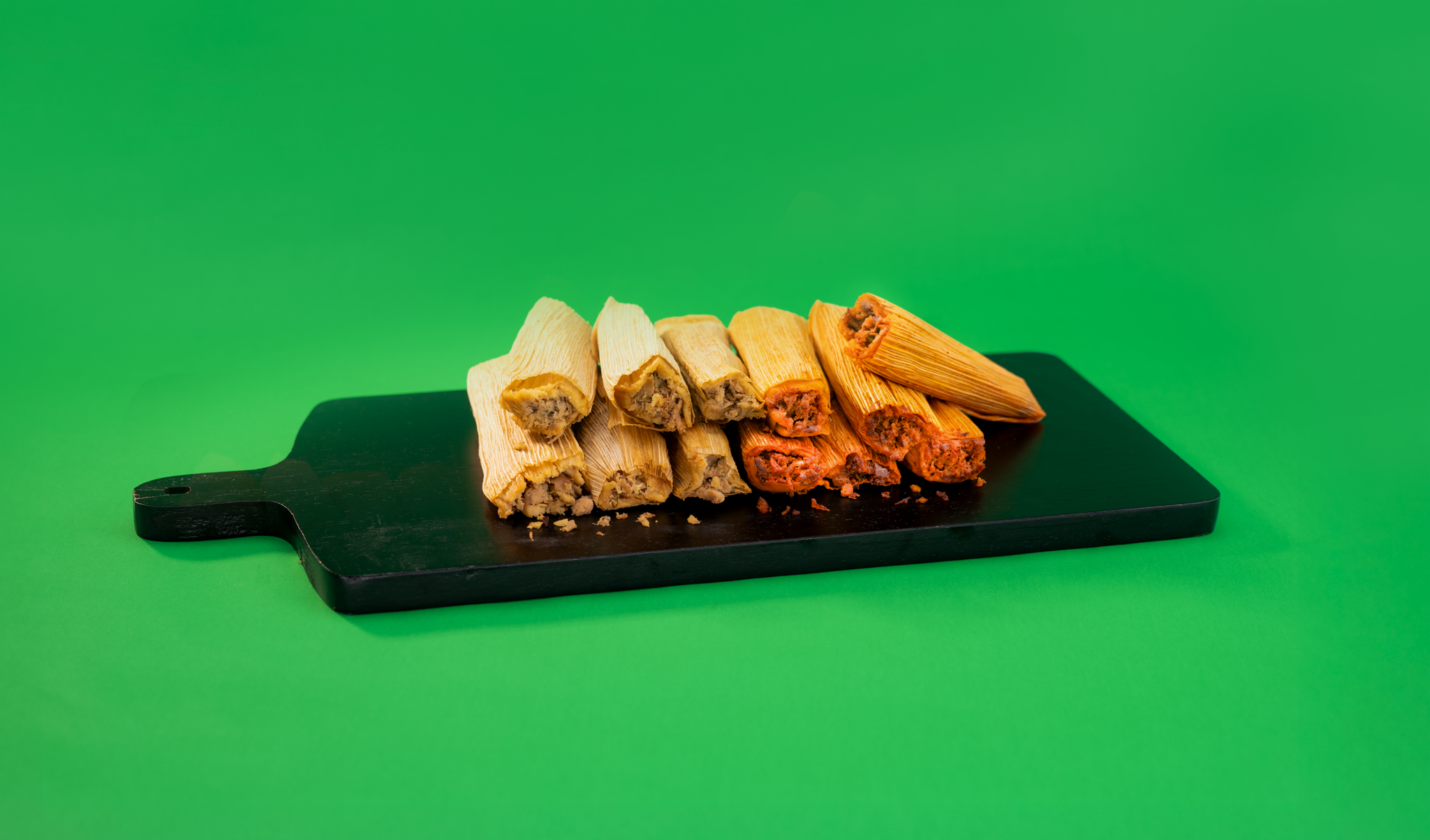 Taco Bueno chicken and pork tamales stacked on black serving board