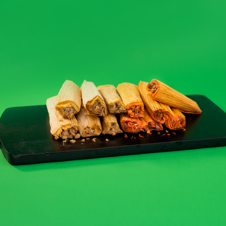 Taco Bueno chicken and pork tamales stacked on black serving board