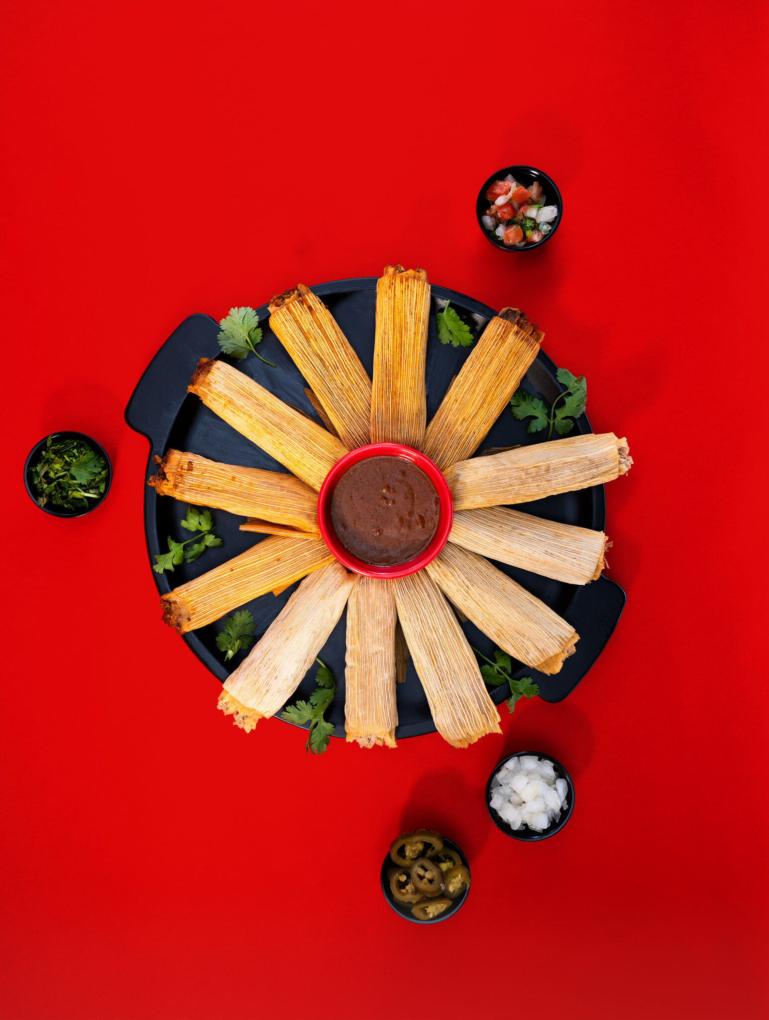 Overhead food photography of Taco Bueno tamales arranged around dipping sauce